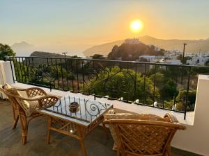 a balcony with a table and chairs and the sunset at Villa Fenia in Aegiali
