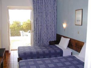 a hotel room with two beds and a window at Oasis Hotel in Masouri