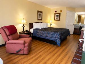 a hotel room with a bed and a chair at Jameson Inn - Perry in Perry +15 photos