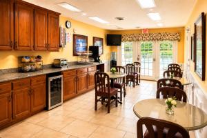 a kitchen with wooden cabinets and tables and chairs at Jameson Inn - Perry in Perry