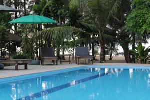 a swimming pool with two chairs and an umbrella at Cousin Koh Kho Khao Beach in Ko Kho Khao