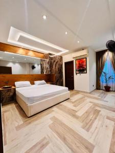 a bedroom with a large white bed and wooden floors at Jinnah Mall Main Boulevard Jubilee Town in Lahore