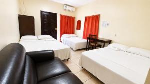 a hotel room with two beds and a leather couch at Hotel King del Centro San Miguel in San Miguel