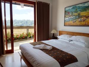 a bedroom with a bed and a large window at Mayong Awan Cita in Munduk