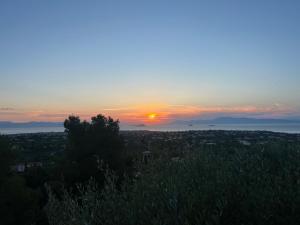 a sunset with the sun setting over a city at Golden Hour on the Hill in Aegina