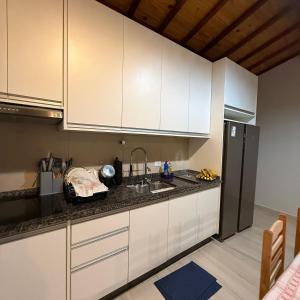 a kitchen with white cabinets and a black refrigerator at Lady Estúdio - Hotel + café em Extrema MG in Extrema