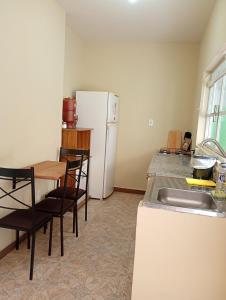 a kitchen with a table and a white refrigerator at Loft no Centro, pertin de tudo! in Itanhandu +14 photos