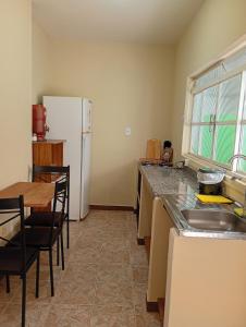 a kitchen with a table and a white refrigerator at Loft no Centro, pertin de tudo! in Itanhandu