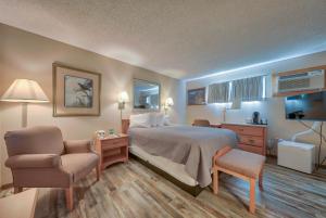 a hotel room with a bed and a chair at A Western Rose in Cody
