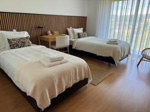 a bedroom with two beds and a table with a chair at Balutinha's house in Barcelos +26 photos