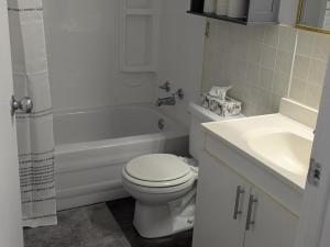 a white bathroom with a toilet and a sink at Le Repere, Beach, Whales, and Ferry in Saint-Siméon +15 photos