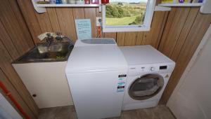 a washing machine and a sink in a small room at Hideaway Beach Cottage in Curio Bay