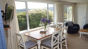 a dining room with a table and chairs and a window at Hideaway Beach Cottage in Curio Bay
