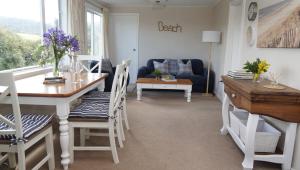 a living room with a table and chairs and a couch at Hideaway Beach Cottage in Curio Bay +14 photos