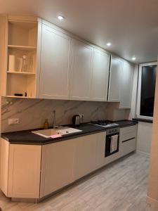 a kitchen with white cabinets and a sink and a stove at Modern & Quiet Apartment in Chişinău