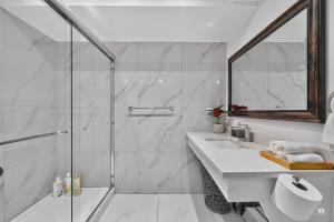 a white bathroom with a shower and a sink at Modern and spacious 3-BR basement suite in Vancouver +18 photos