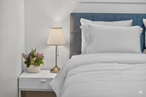 a white bed with a blue headboard and a lamp at Modern and spacious 3-BR basement suite in Vancouver