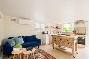 a living room with a blue couch and a kitchen at Green Scape - Whale Beach in Whale Beach