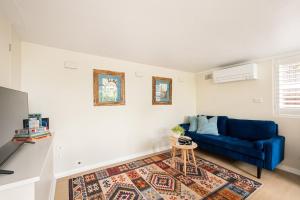 a living room with a blue couch and a rug at Green Scape - Whale Beach in Whale Beach