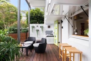a patio with chairs and a table on a deck at Green Scape - Whale Beach in Whale Beach