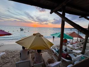 a group of people sitting on the beach under an umbrella at Chiki luki in Playa Blanca
