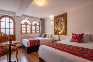 a bedroom with two beds and a table and a chair at Hotel Monasterio del Inka Cusco in Cusco +79 photos