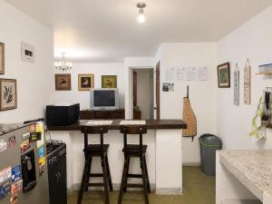 a kitchen with a counter with stools and a refrigerator at ECOHostal las Hamacas in Villamaría