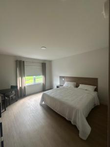 ein Schlafzimmer mit einem großen weißen Bett und einem Schreibtisch in der Unterkunft Hotel W Des Cantons in Weedon-Centre