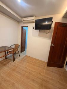 ein Zimmer mit einem Tisch und einem Fernseher an der Wand in der Unterkunft Hotel Riomar in Iquitos