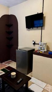 a room with a refrigerator and a table and a tv at Loft Industrial con fogatero in Mineral del Monte