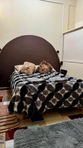 a bed with a black and white blanket and pillows at Loft Industrial con fogatero in Mineral del Monte