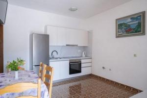 a kitchen with white cabinets and a table and a refrigerator at Apartments by the sea Grscica, Korcula - 4487 in Prizba