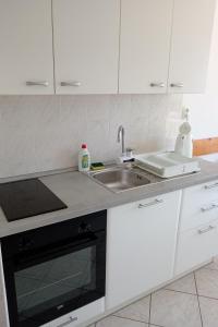 a kitchen with white cabinets and a sink at Apartment Grscica 4487a in Prizba +16 photos