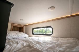a bedroom with a white bed and a window at Ouachita Outpost RV Park in Hodgen