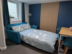 a blue bedroom with a bed and a table and a tableablish at Stylish town flat in Bude, with secure parking in Bude