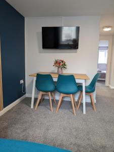 a table with four chairs and a television on a wall at Stylish town flat in Bude, with secure parking in Bude