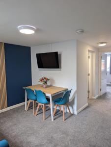 a dining room with a table and blue chairs at Stylish town flat in Bude, with secure parking in Bude