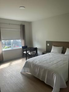 ein Schlafzimmer mit einem Bett, einem Tisch und einem Fenster in der Unterkunft Hotel W Des Cantons in Weedon-Centre
