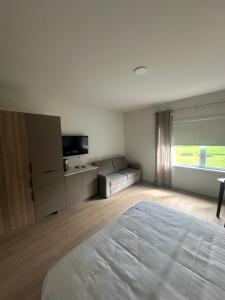ein weißes Schlafzimmer mit einem Bett und einer Couch in der Unterkunft Hotel W Des Cantons in Weedon-Centre + 1 Foto