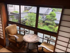 a balcony with two chairs and a table and a window at Guesthouse Nara Backpackers in Nara