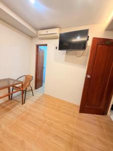 ein Wohnzimmer mit einem Tisch und einem Fernseher an der Wand in der Unterkunft Hotel Riomar in Iquitos