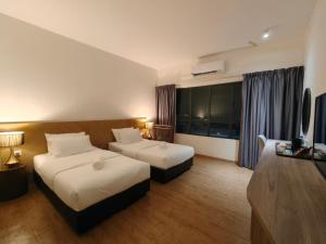 a hotel room with two beds and a television at SF Roomstay Tunjong in Kota Bharu