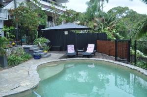 a small pool with two chairs and an umbrella at Green Scape - Whale Beach in Whale Beach