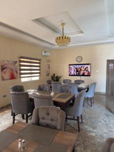 a dining room with tables and chairs and a tv at Zamin Suites in Kano