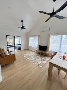 a living room with a ceiling fan and a table at Hildas Villa in Arorangi