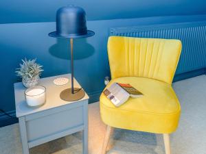 a yellow chair next to a table with a lamp at River Test View in Chilbolton