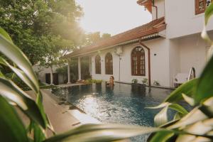 a woman sitting in a swimming pool next to a house at Airport Transit Villa in Minuwangoda