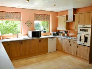 a kitchen with wooden cabinets and a microwave at Field House in Baschurch