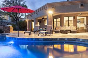 ein Pool mit Tisch und Sonnenschirm neben einem Haus in der Unterkunft Hillside Tranquility in Fountain Hills