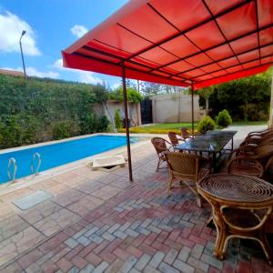 a patio with a table and chairs under a red umbrella at فيلا تسنيم للعائلات in Naj‘ al Aḩwāl